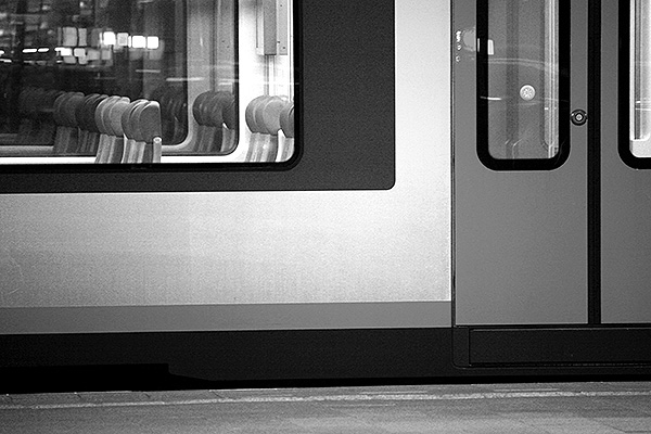 Zwart wit foto van trein op een station.